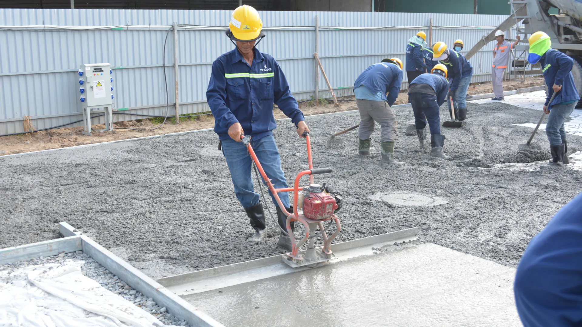 Construction workers smoothing and finishing a concrete floor slab for a floor system design project in Chesterfield
